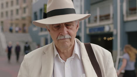 portrait d'un homme âgé élégant en vacances touriste à l'air sérieux portant un costume blanc et un chapeau enlevant des lunettes