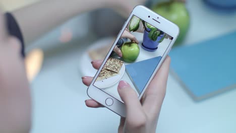 Mobiles-Fotoessen.-Weibliche-Hand,-Die-Lebensmittelzusammensetzung-Aus-Grünem-Apfel-Und-Snack-Herstellt