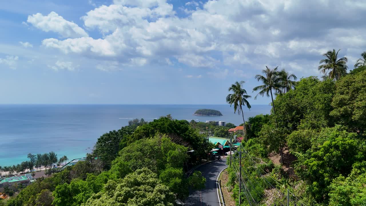 드론 영상은 태국 푸켓의 해안 도로를 따라 밝은 낮에 울창한 초록색과 조용한 바다 풍경을 포착합니다.