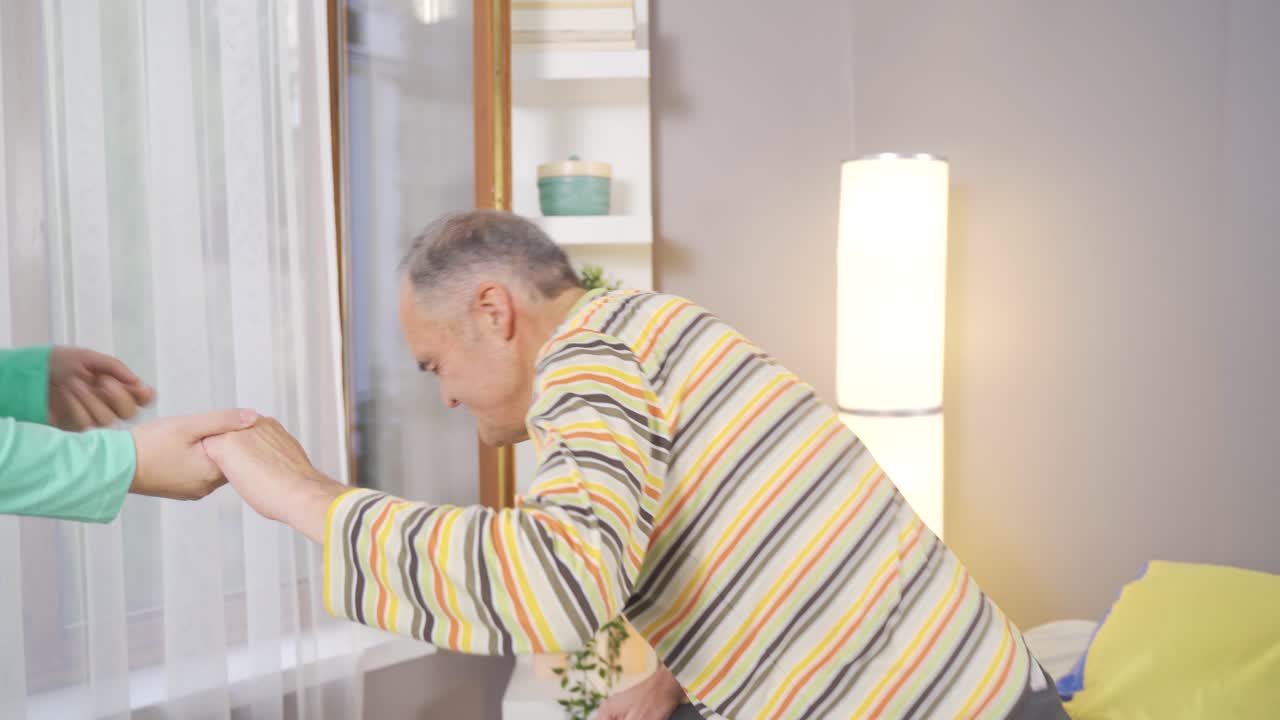 여성 구급대원이 집에서 나이 많은 남자의 손을 잡고 그녀를 세우고 있습니다.
