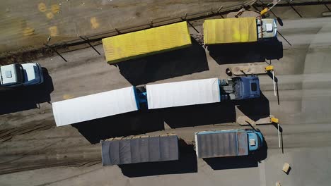 Cargo-trucks-lined-up-at-a-loading-dock,-sunny-day,-aerial-view