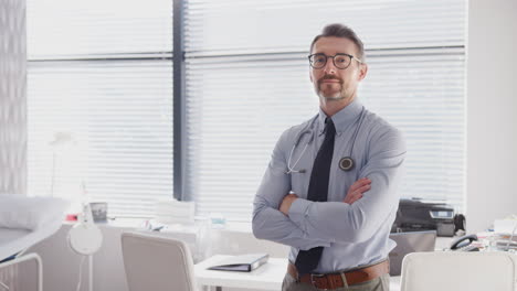retrato de un médico adulto sonriente de pie junto al escritorio en la oficina