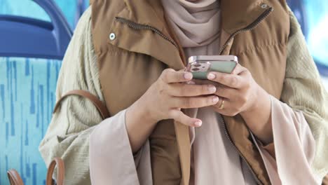 woman in hijab using her phone on a bus