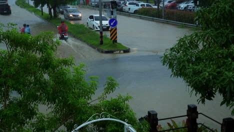 cars and scooters driving through the flood after raining very heavy in hat yai, thailand