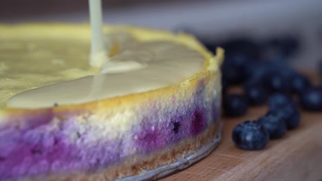 mesmerizing view of thick creamy sauce covering top of blueberry cheesecake