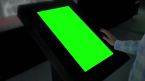 concepto de pantalla verde - mujer mirando un quiosco de exhibición verde en blanco en la exposición