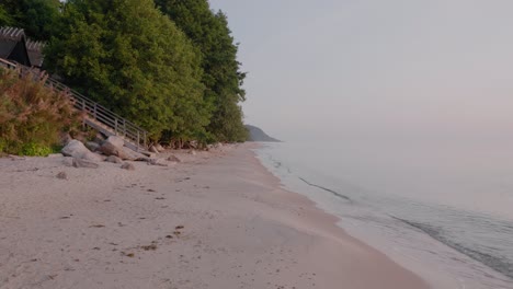 Knäbäckshusen-Beach-In-Österlen-With-Staircase-and-Cottage-By-The-Beech-Trees-in-The-Summer-Morning,-Static-Wide-Shot