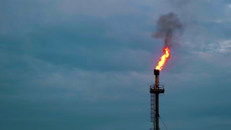 Fuego-Ardiendo-Desde-La-Chimenea-De-Una-Planta-De-Gas-O-Petróleo-Bajo-Un-Cielo-Nublado