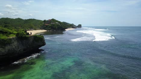 aerial forward shot of beautiful coastline with waves and sandy beach during sunny day in indonesia, java