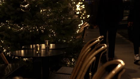 Shot-of-popular-roadside-cafe-chairs-and-tables-with-locals-walking-by-at-night-time