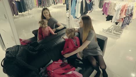 young-beautiful-mother-with-a-cute-baby-in-the-store-trying-on-clothes-in-front-of-a-mirror