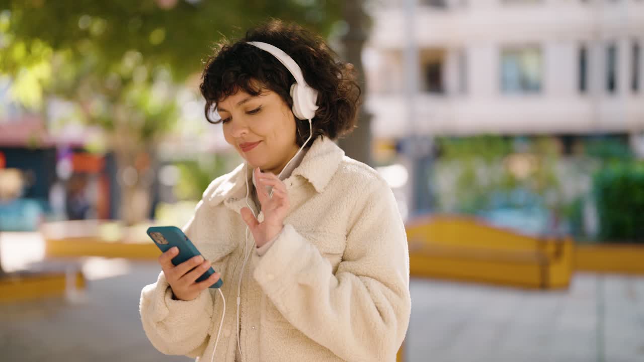 Young hispanic woman smiling confident listening to music at park