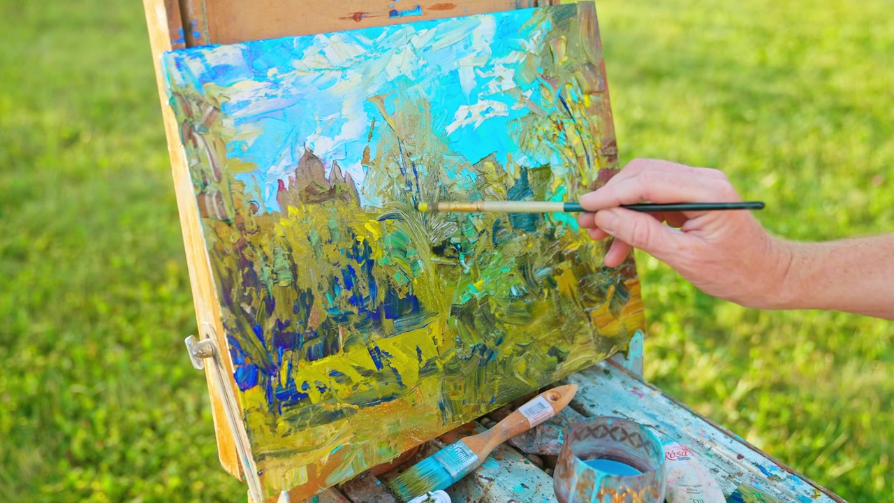 Mano d'artista che dipinge un paesaggio impressionista all'aperto