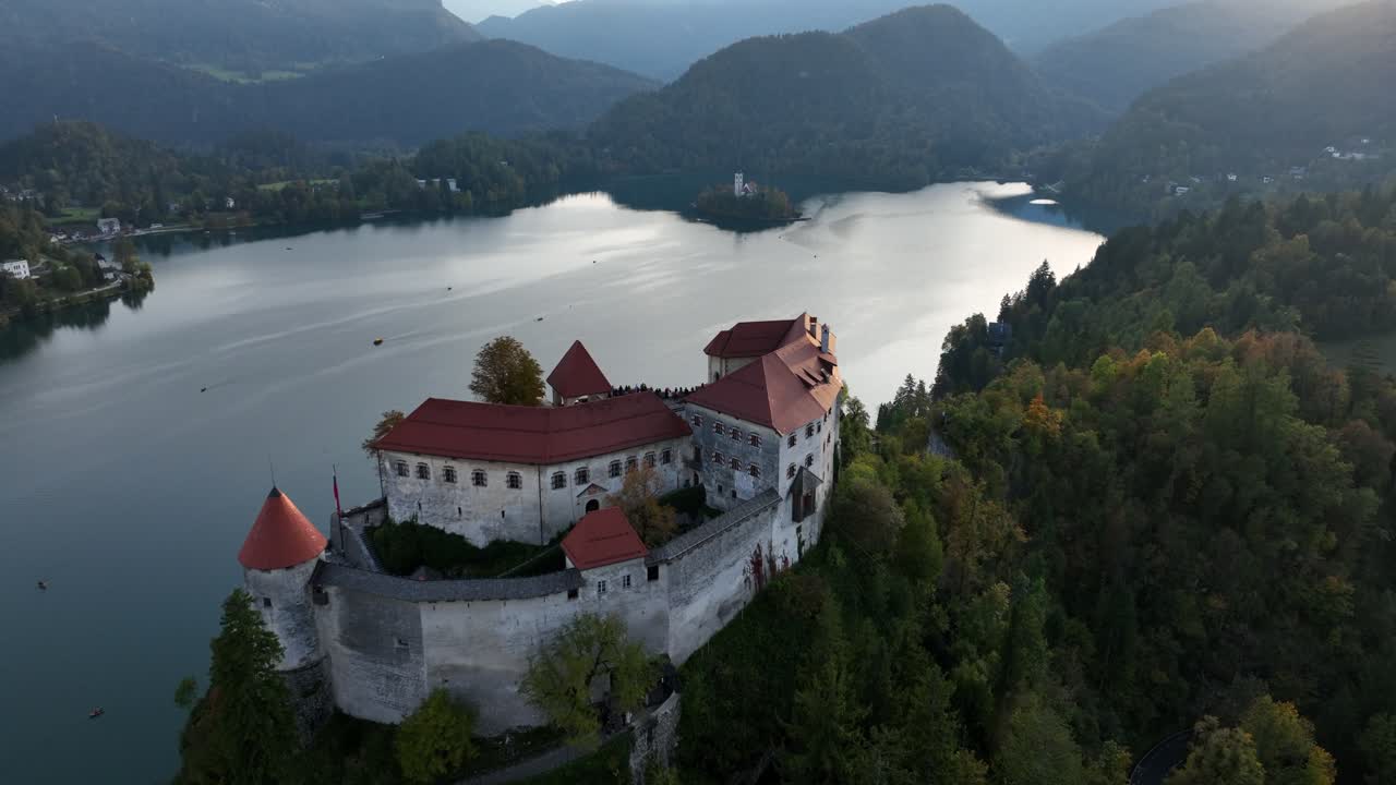 Antico castello in riva a un lago sereno al tramonto, che evoca tranquillità e storia