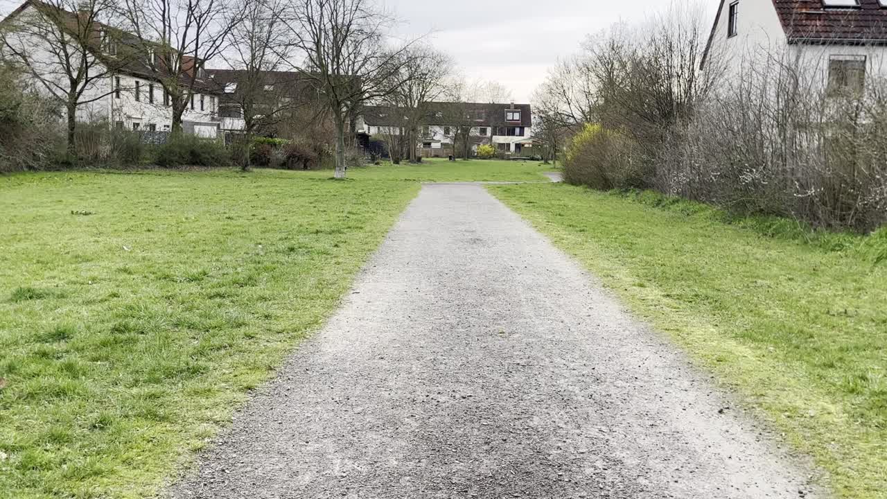 park path on a meadow in a small settlement with white houses