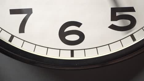 white clock face close up in time lapse on dark grey wall