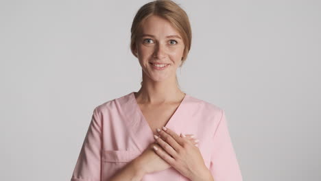 caucasian female doctor holding hands on heart.