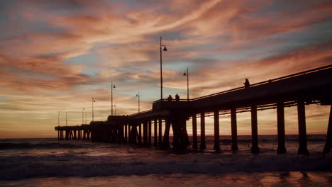 scenic pier silhouette at sunset with vibrant sky and ocean waves