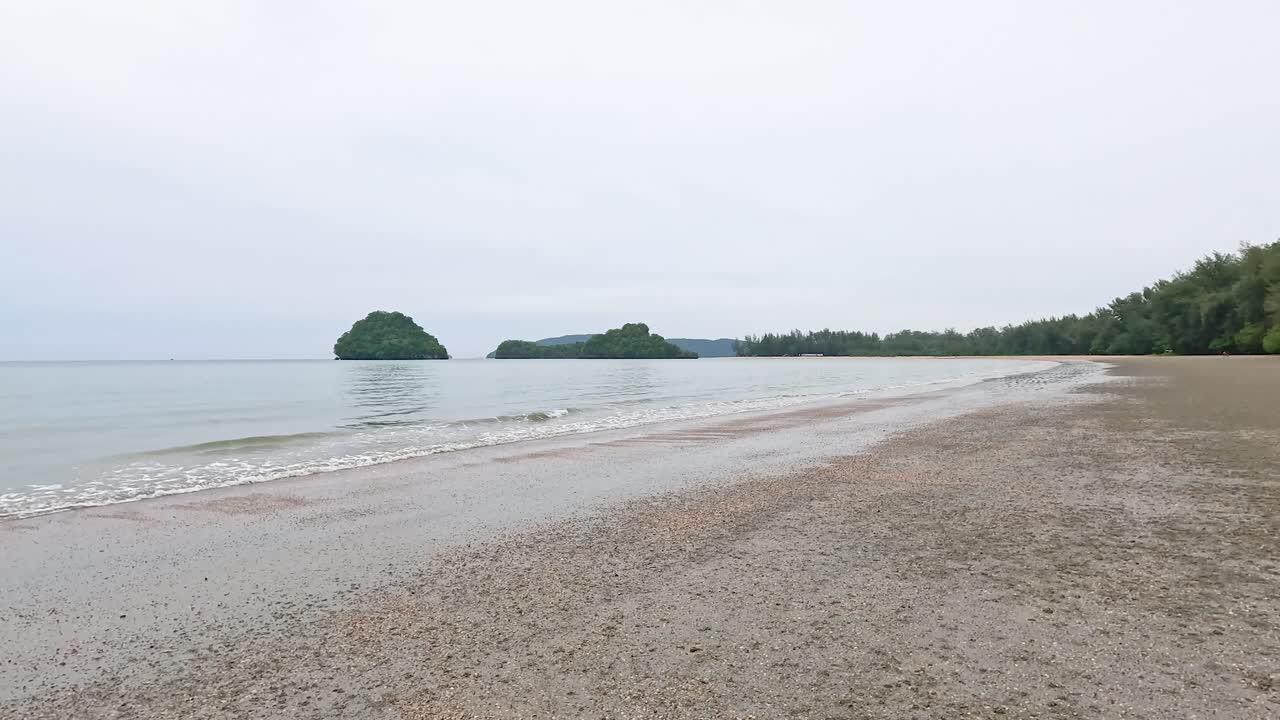 태국 크라비에 있는 노파라트 타라 해변의 조용한 풍경, 평화로운 환경에서 조용한 물과 구름이 가득한 하늘을 보여줍니다.