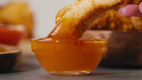 dipping fried chicken in orange sauce