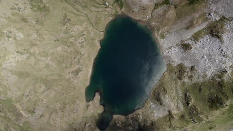 4k descending top-down drone shot over ibón de acherito in the western valleys natural park, aragonese pyrenees, spain. a breathtaking aerial view of the alpine lake surrounded by mountains.