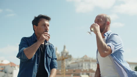 gay couple clinking glasses and drinking champagne outdoors