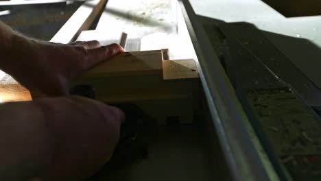 a woodworker places a piece of wood on a table saw with a stacked dado set and pushes it through to make multiple cuts to create a tenon in slow motion