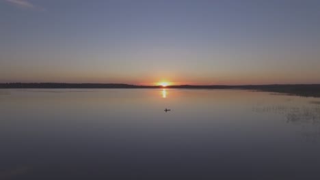 Aerial-Flying-Over-Fisherman-in-a-Boat-on-a-Lake-on-a-Calm-Summer-Evening-at-Sunset