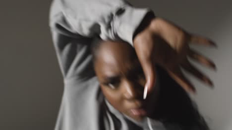 Close-Up-Studio-Portrait-Shot-Of-Young-Woman-Wearing-Hoodie-Dancing-With-Low-Key-Lighting-Against-Grey-Background