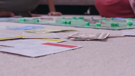 ground level view of children and adults playing the classic board game monopoly.