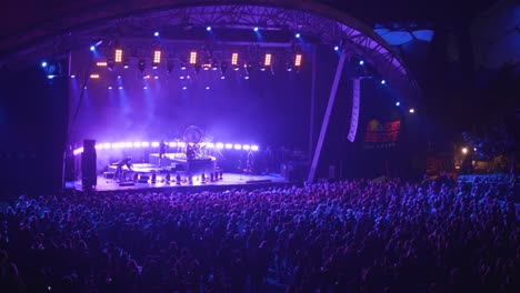 crowd of fans waiting for the band to perform on the stage at night on eden project in cornwall, uk. - wide