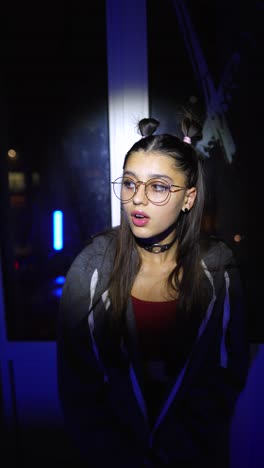 close-up of a young woman wearing glasses under different colored lights