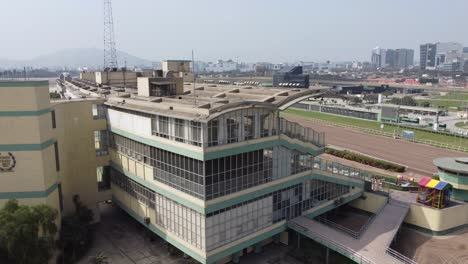 Drone-video-4k-video-of-a-horse-racetrack-in-Lima,-Peru-called-"Hipodromo-de-Monterrico"-Drone-flies-up-revealing-the-spectator-stands,-dirt-track-and-buildings-in-the-distance