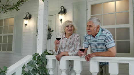 Pareja-Caucásica-De-Ancianos-Bebiendo-Vino-En-El-Porche-De-Casa.-Feliz-Familia-Jubilada-Madura-Descansando