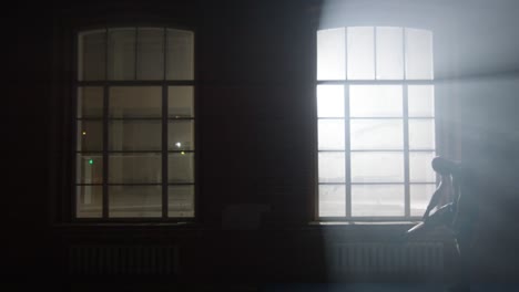 man sitting by window at night