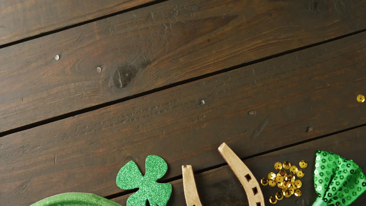 Video of st patrick's green hat, shamrock and horseshoe with copy space on wooden background