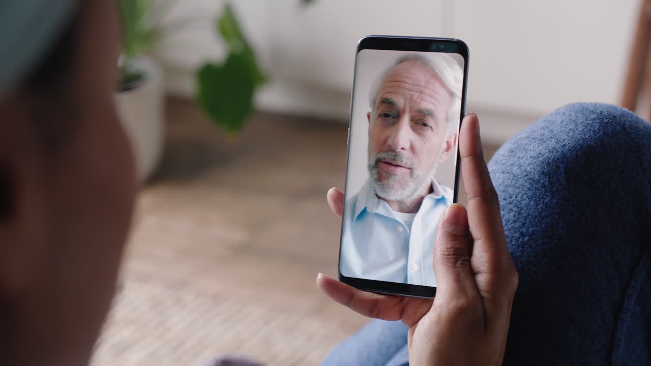 mujer joven teniendo video chat usando teléfono inteligente en casa hablando con el abuelo mostrando el estilo de vida de compartir apartamento disfrutando de la comunicación por teléfono móvil