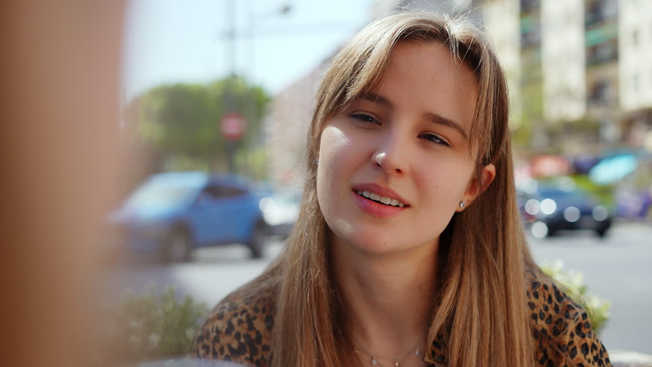 Young Woman Enjoying a Conversation at an Outdoor Cafe
