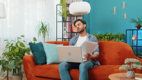 stressed indian man looking at unpaid bank debt loan doing paperwork planning budget throws bills