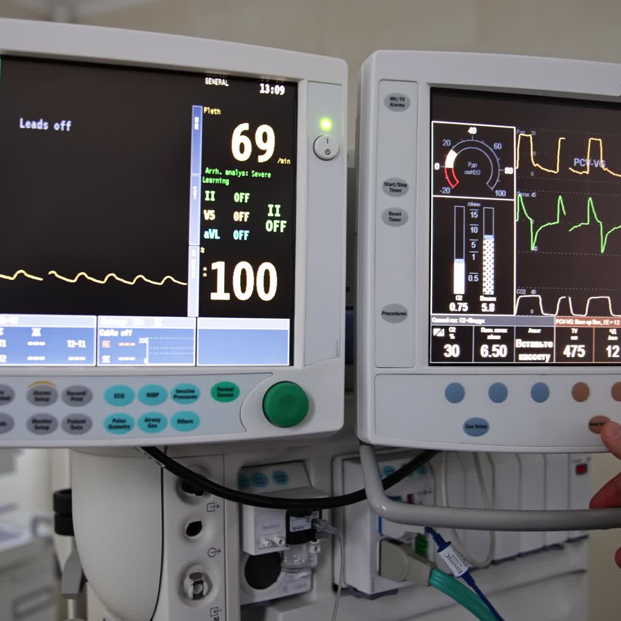 Male anesthesiologist wearing black uniform, surgical mask and cap stands at equipment. Medic pressing the buttons on the lung system monitors