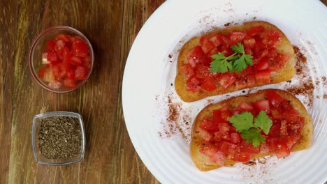 tomato sandwich or italian bruschetta with parsley rotates slowly on turntable in white plate. mediterranean food.