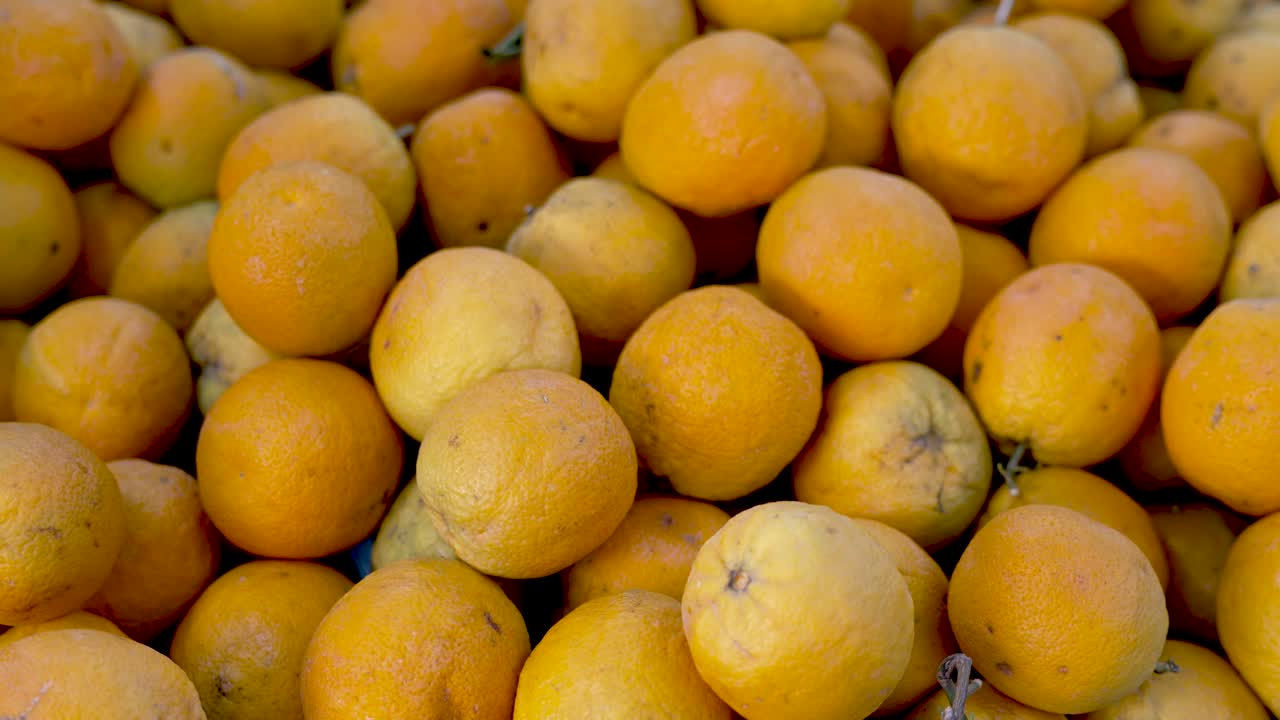 Brightly colored oranges fill the frame, showcasing their rich hues under the warm sun. A lively market atmosphere surrounds these fresh fruits, promising sweetness and nourishment
