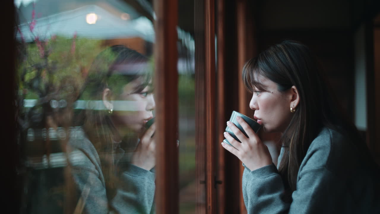 Woman drinking tea by the window