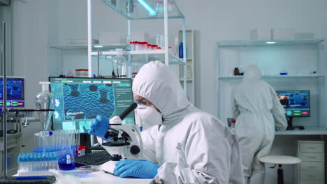 scientist in ppe suit working in laboratory using modern microscope