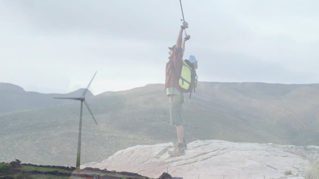 hiker raising trekking poles on rocky summit, overlaying animated turbine icons for technology