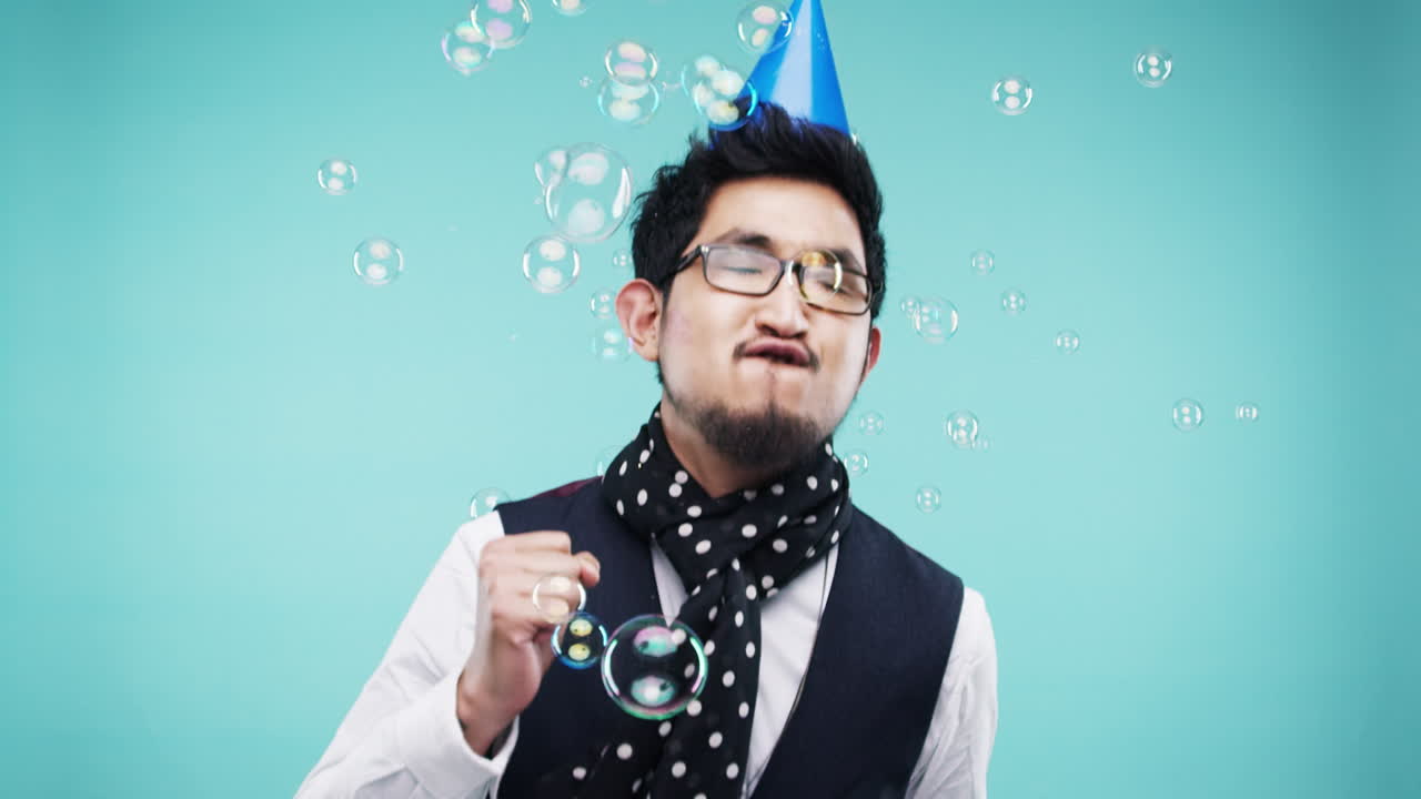 파티 모자를 입고 거품을 불어넣는 남자