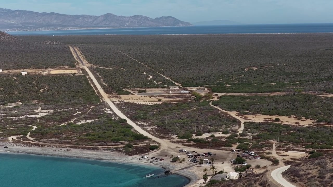 Vista aérea de uma longa estrada de terra reta que leva à praia em Ensenada de los Muertos, México.