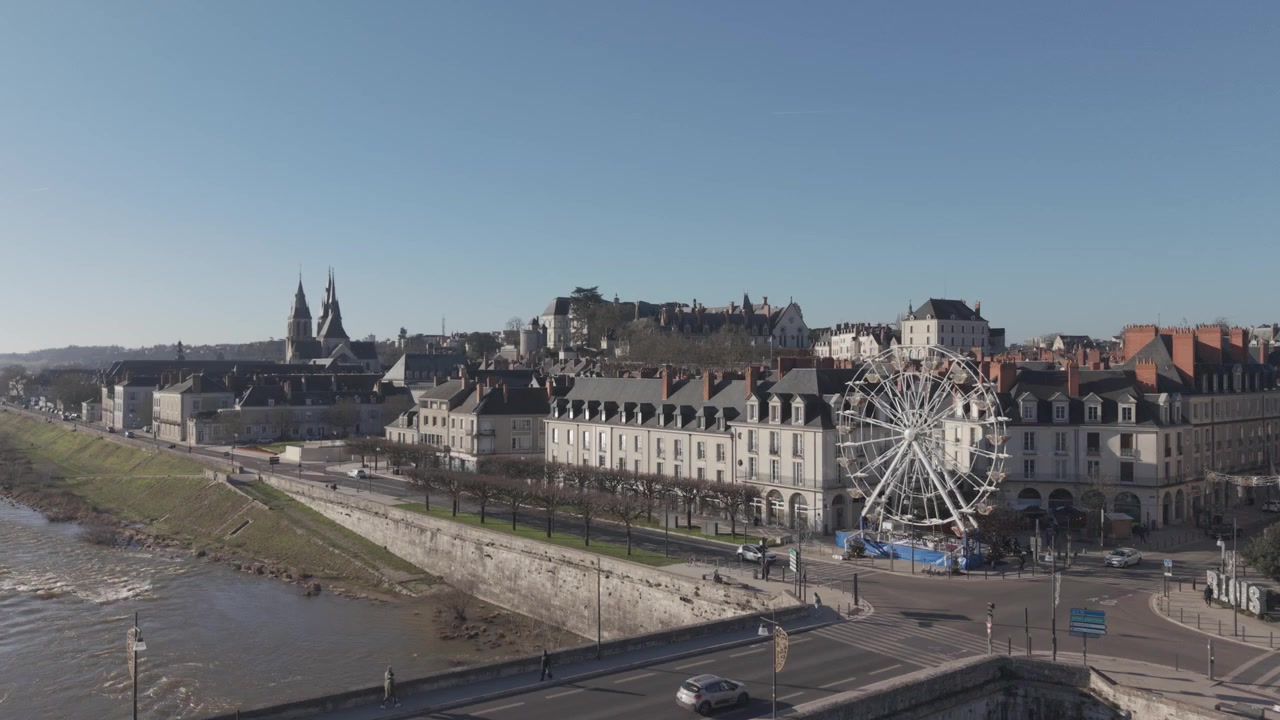 Et luftfoto viser Blois' flodbred med et tivoli-pariserhjul og tårnene fra katedralen og slottet