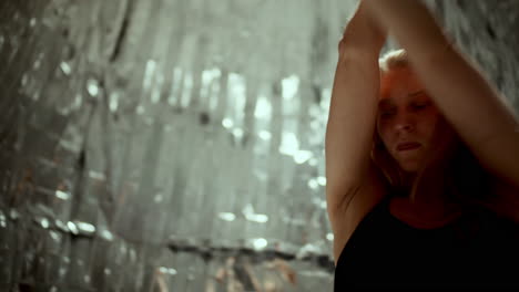 young woman performing contemporary dance against metallic backdrop