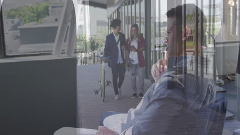 sitting indoors, man sees reflection of two people walking with bicycle outside